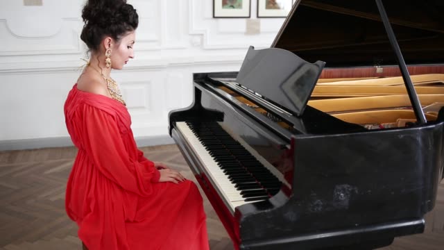 elegante-Dame-im-roten-Kleid-und-teuren-Schmuck-spielt-das-Klavier-im-Raum