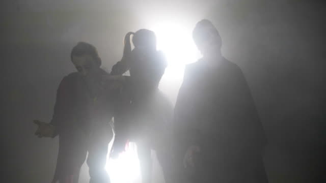 Horror-zombie-friends-males-and-female-dancing-in-foggy-forest-on-halloween-night-in-slow-motion