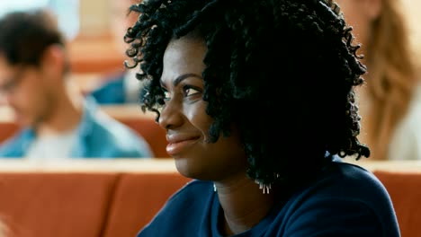 Portrait-of-a-Smart-and-Beautiful-Young-Black-Girl-Listening-to-a-Lecture-in-a-Classroom-Full-of-Multi-Ethnic-Students.-Young-People-Study-in-the-University.