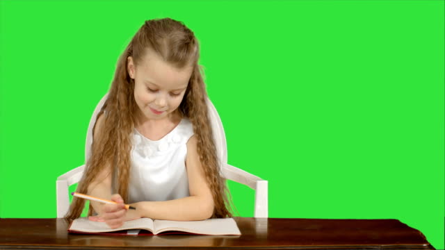 Kleines-Mädchen-schreibt-in-Heft-auf-einem-Green-Screen,-Chroma-Key