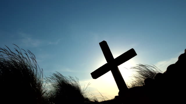 Silhouette-of-man'-hand-raised-cross-over-the-sunrise---concept-for-religion