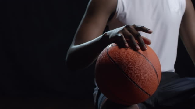 Nicht-erkennbare-Basketball-Spieler-sitzen-auf-schwarzem-Hintergrund