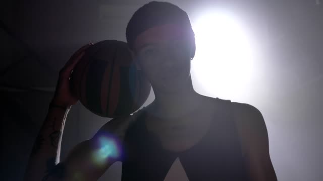 Basketball-player-with-tattoos-holding-ball-on-his-shoulder-and-looking-at-camera
