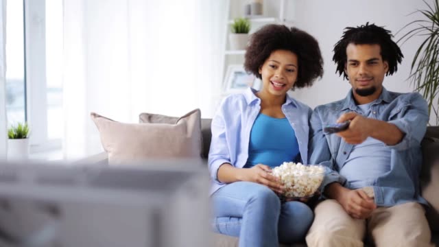 lächelnde-Paar-mit-Popcorn-zu-Hause-vor-dem-Fernseher
