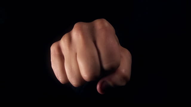 Fist-appearing-from-black-background-towards-the-camera