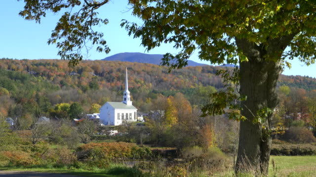 weiße-Kirche-in-Stowe,-eingerahmt-von-Baum-und-einem-Hügel-mit-Herbstlaub