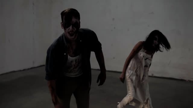 Creepy-scene-of-a-two-male-and-female-zombies-coming-on-in-empty-placement-with-white-walls.-Halloween,-filming,-staging-concept