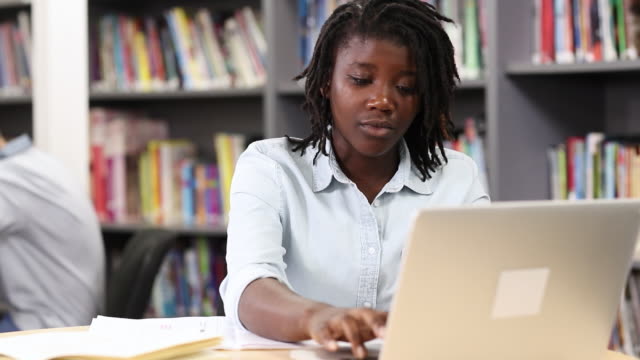 Female-High-School-Student-Working-At-Laptop-In-Library