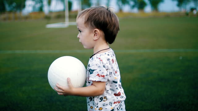 Kleiner-Junge-hält-den-Ball-in-seine-Hände-auf-dem-Fußballplatz