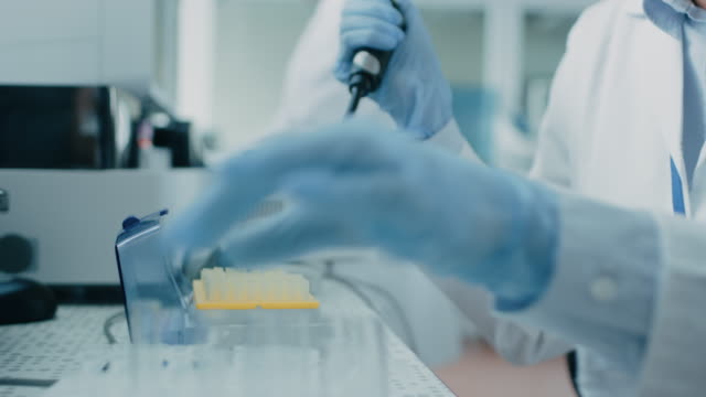 Close-up-of-the-Female-Scientist's-Hand-in-Glove-Using-Micro-Pipette-while-Working-with-Test-Tubes.-People-in-Innovative-Pharmaceutical-Laboratory-Study-Genetics-and-Pharmaceutics.