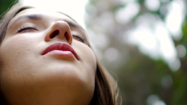 Low-angle-shot-woman-face-with-closed-eyes-meditates-feels-united-with-nature