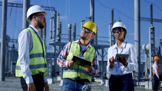 Three-electrical-workers-reviewing-documents-on-a-tablet