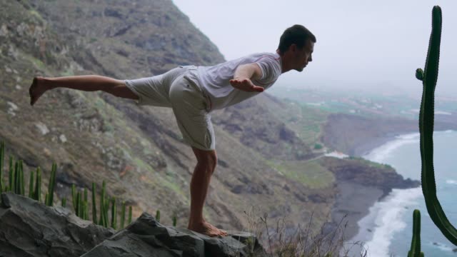 Fit-junger-Mann-praktiziert-Sonne-Anrede-Yoga-in-den-Bergen-für-Ozean.-Junger-Mann-genießen-Meditation-und-Yoga.-Fitness,-Sport,-People--und-Lifestyle-Konzept---junger-Mann,-der-Yoga-Übungen
