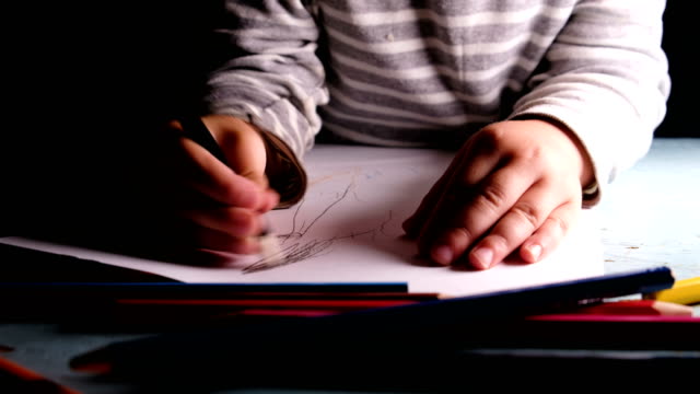 Niño-pequeño-dibuja-lápiz-negro-en-una-hoja-de-primer-plano-de-papel