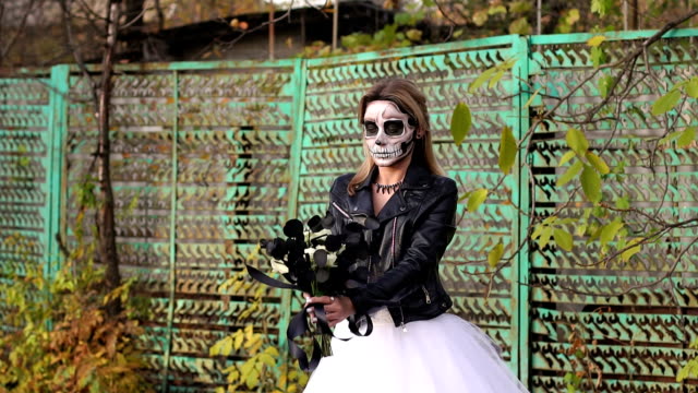 Eine-Braut-mit-einem-gruselige-Schädel-Make-up-für-Halloween-in-einer-verlassenen-Stadt.