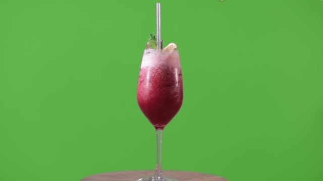Red-cocktail-on-green-background,-cocktail-rotates-on-hromokoy-background,-alcoholic-cocktail-on-green-background