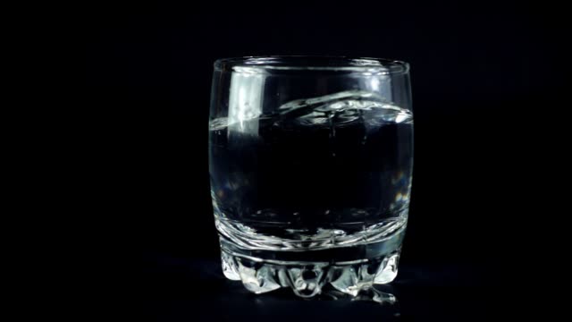 Water-in-a-glass-on-a-black-background.-Slow-motion.