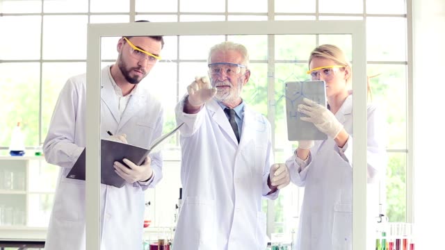 Wissenschaftsteam-Lehrer-und-Schüler-arbeiten-mit-Chemikalien-auf-Glas-Board-im-Labor
