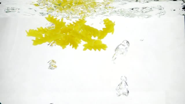 Macaroni-pasta-splash-falling-into-boiled-water,-shot-in-slow-motion-on-white-background