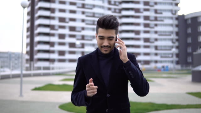 Happy-stylish-businessman-hear-good-news-on-the-phone-and-rejoices-with-happy-emotions-outdoors-near-office-building