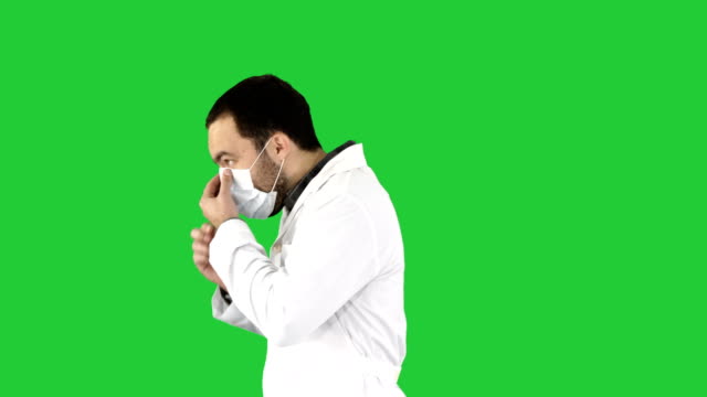 Walking-doctor-putting-on-mask-and-cap-on-a-Green-Screen,-Chroma-Key