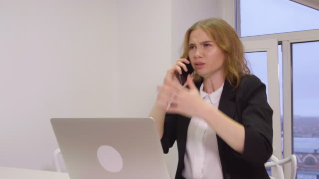 Angry-business-woman-scolding-while-mobile-conversation-in-business-office