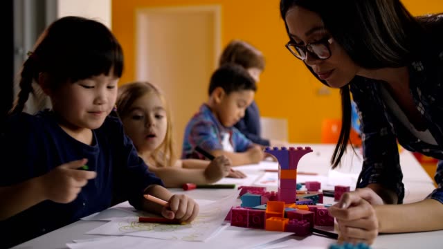 Kindergarten-teacher-helping-kids-at-art-class