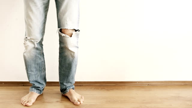 Funny-male-showing-Dance.-Legs-in-torn-jeans-against-the-white-wall.