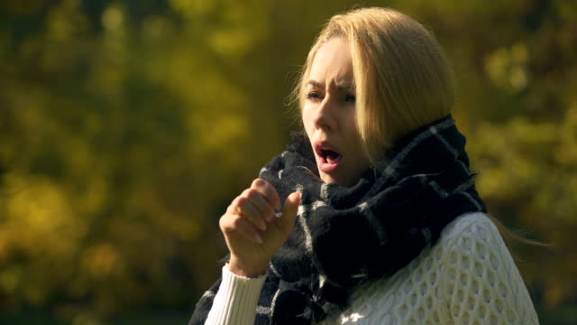 Sick-woman-in-scarf-coughing-and-sneezing-in-autumn-park,-caught-cold,-immunity