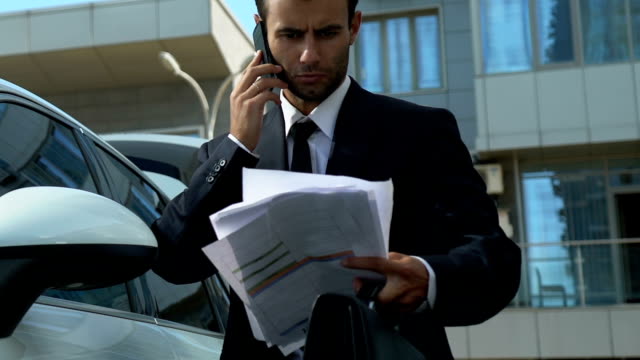 Empresario-hablando-por-teléfono-cerca-de-coche,-para-resolver-los-problemas-financieros-de-la-empresa