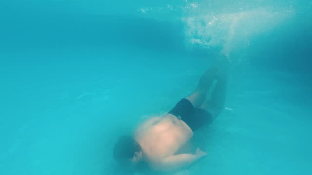 Junger-Mann-schwimmt-unter-Wasser-in-einem-Schwimmbad