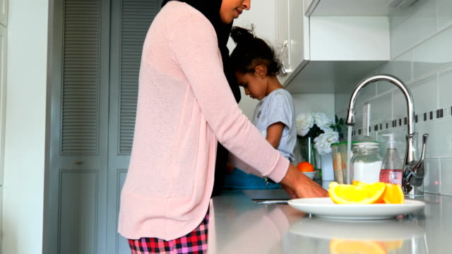 Young-mother-washing-dishes-in-kitchen-at-home-4k