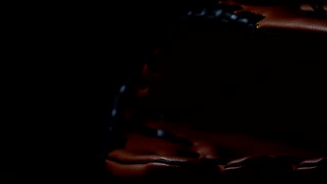 Werfen-Sie-einen-Baseball-mit-einem-Baseballhandschuh,-in-ein-dunkles-Licht-gelegt