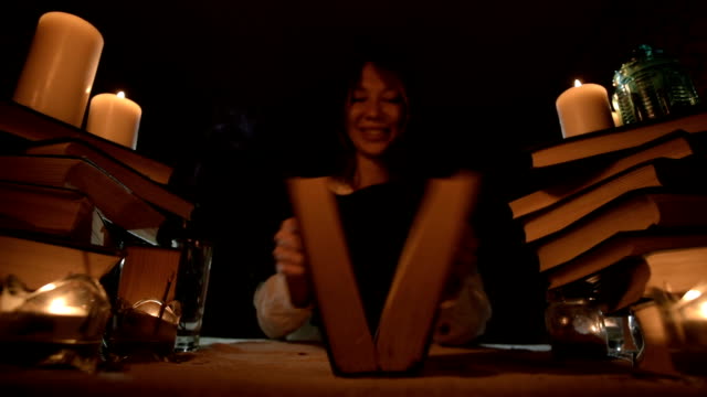 Nahaufnahme-eines-gelangweilten-Mädchenzauberers-in-einem-dunklen-Raum-bei-Kerzenschein-tummelt-sich-in-einem-Buch-und-meditiert.