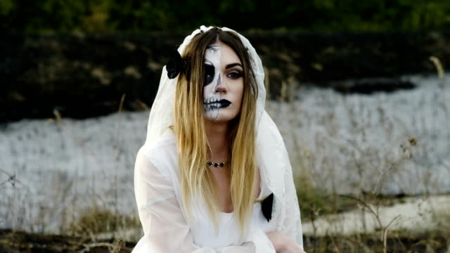 La-joven-con-maquillaje-espeluznante-para-Halloween-en-un-vestido-de-novia-blanco.-4K