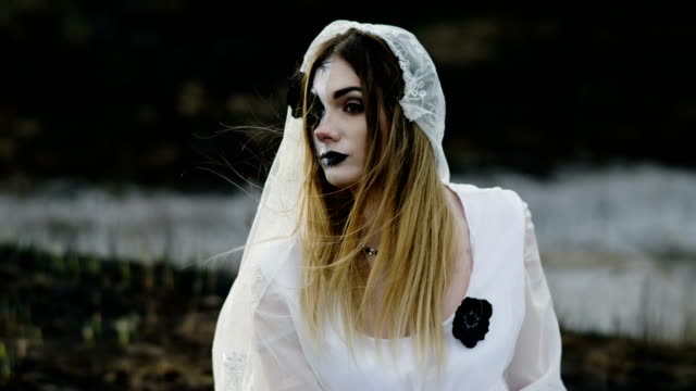 The-young-woman-with-spooky-make-up-for-Halloween-in-a-white-bride-dress.-4K