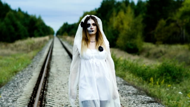 Die-junge-Frau-mit-Make-up-der-toten-Braut-für-Halloween-auf-dem-Bahngleis.-4K