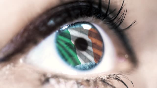 woman-blue-eye-in-close-up-with-the-flag-of-Ireland-in-iris-with-wind-motion.-video-concept
