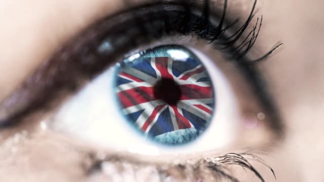 Frau-blaues-Auge-in-Nahaufnahme-mit-der-Flagge-des-Vereinigten-Königreichs-in-Iris-mit-Windbewegung.-Videokonzept