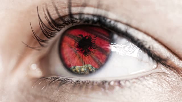 mujer-ojo-verde-en-primer-plano-con-la-bandera-de-Albania-en-el-iris-con-el-movimiento-del-viento.-concepto-de-vídeo