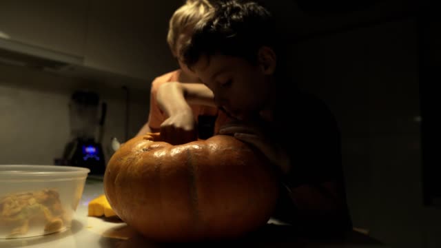 Happy-halloween.-Father-and-sons-carving-pumpkin-on-the-table-in-the-home.-Family-preparing-for-holiday.-Top-view.-Close-up