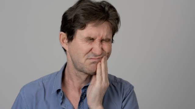 Ein-erwachsener-Mann-mit-Zahnschmerzen-hält-eine-Check-hand