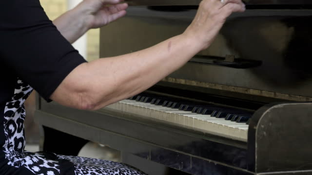 Alte-Frau-zu-öffnen,-Deckel-und-anfangen-zu-spielen-Klavier