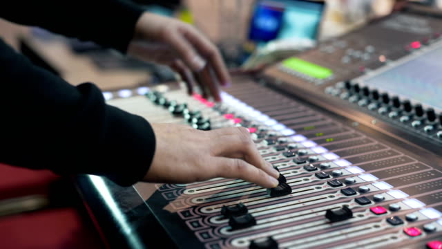 Audio-engineer-working-on-a-professional-console,-moving-faders,-mixing-music