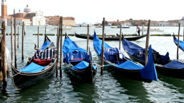 Schöne-schwarze-Gondeln-stehen-und-Schaukeln-auf-den-Wellen-des-Canal-Grande-in-Venedig