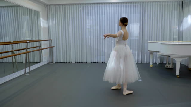 Ballerina-in-white-ballet-tutu-and-pointe-shoes-whirled-in-ballet-studio
