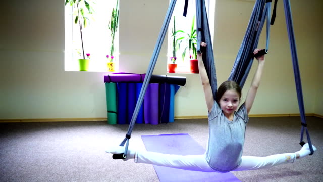 Schoolgirl-sits-on-twine-on-acrobatic-ropes
