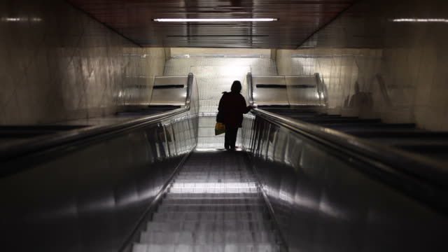 Frau-reitet-auf-Rolltreppe-im-Untergrund