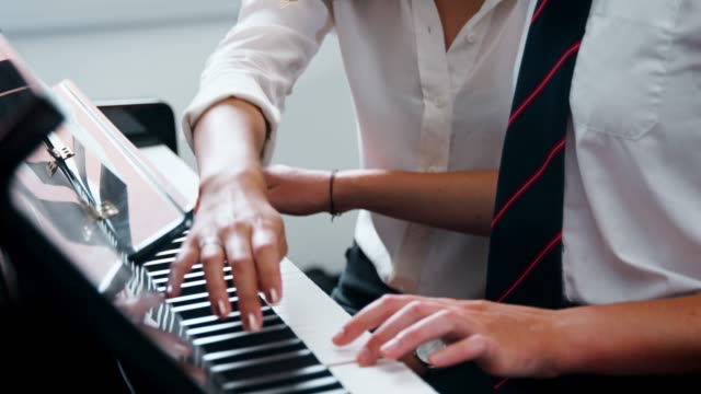 Estudiante-femenino-con-el-maestro-tocando-el-Piano-en-la-lección-de-música