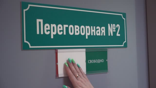 Mujer-se-mueve-la-placa-que-ocuparán-en-la-puerta-con-el-texto-ruso,-sala-de-reuniones